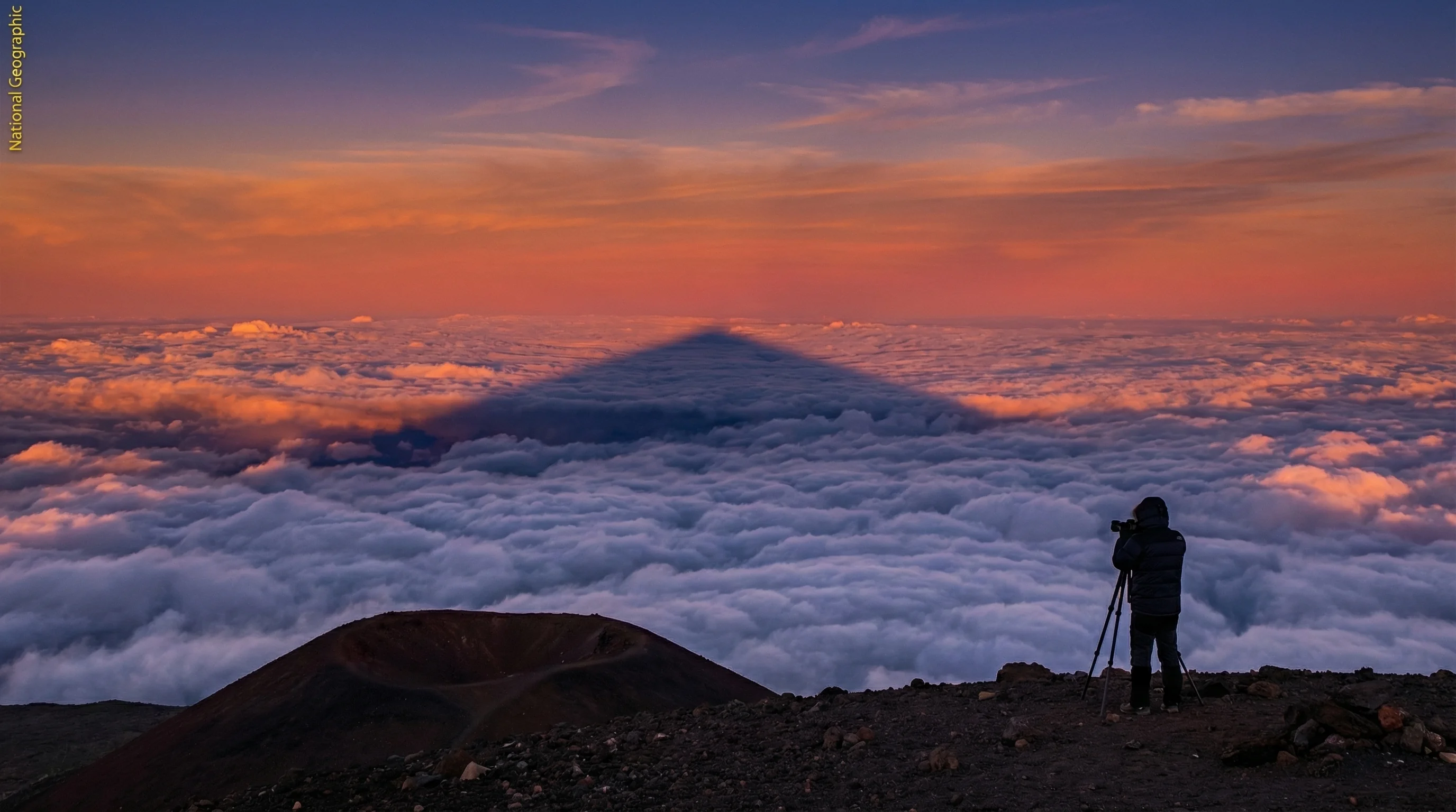 Mauna Kea sunset creates stunning mountain shadow across clouds before the best stargazing begins Mauna Kea sunset shadow stretching across clouds before stargazing begins